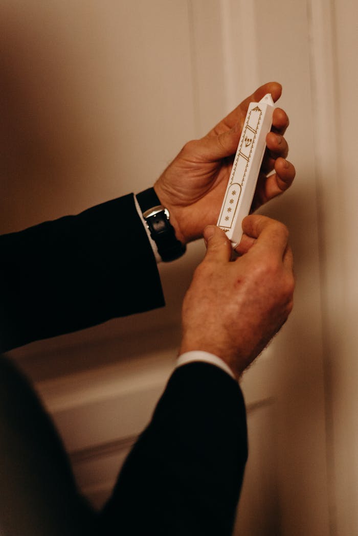 A close-up of hands installing a mezuzah on a doorpost, symbolizing Jewish tradition.